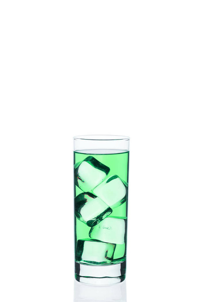 Bebida verde con cubitos de hielo en un vaso sobre fondo blanco. Cóctel frío exótico. Líquido tónico directamente de la barra
. - Foto, imagen