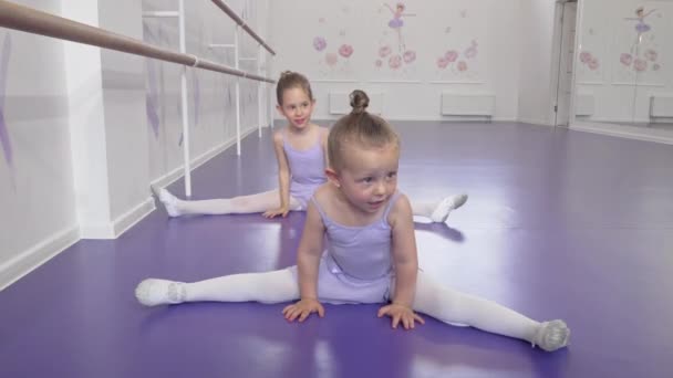 Twee schattige kleine ballerina's meisjes die zich uitstrekken op Ballet klasse doen splitsingen - Video
