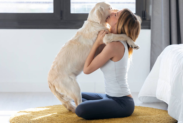Ładna młoda kobieta przytulanie jej psa siedząc na podłodze w domu. - Zdjęcie, obraz