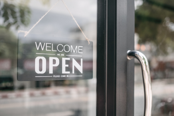 Closeup of open and welcome to store sign board at the door. - 写真・画像