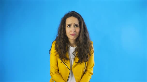 Jeune femme confus en veste jaune dans Studio avec fond bleu
. - Séquence, vidéo