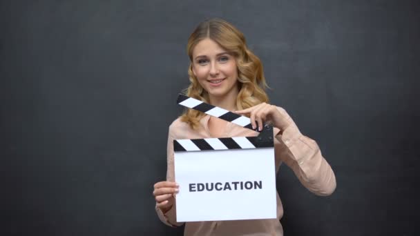 Girl using clapperboard with word Education, start of school year, graduation - Imágenes, Vídeo