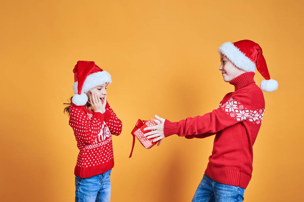 Boy handing Christmas present to surprised girl - Photo, Image