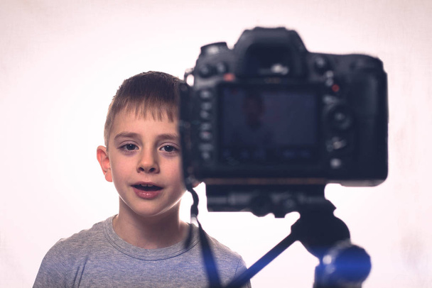 L'écolier dit quelque chose sur un caméscope. Jeune blogueur vidéo. Caméra au premier plan
 - Photo, image