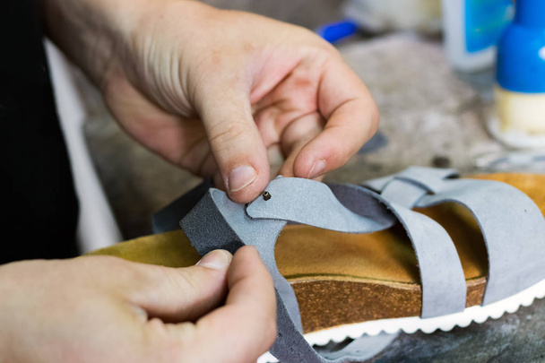 Mâle cordonnier mains réparer une sandale en cuir
. - Photo, image