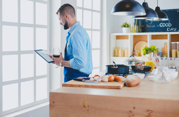 Mies seuraavat resepti digitaalinen tabletti ja ruoanlaitto maukasta ja terveellistä ruokaa keittiössä kotona - Valokuva, kuva