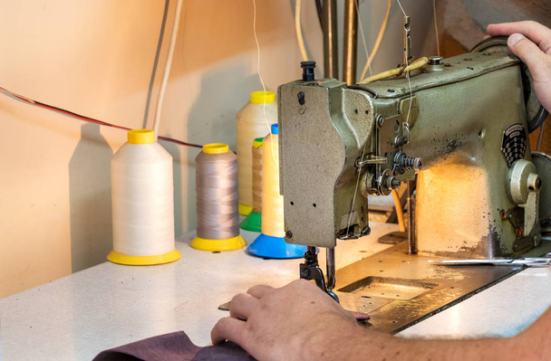 Um sapateiro masculino mãos, costura de couro com uma velha máquina de costura
. - Foto, Imagem