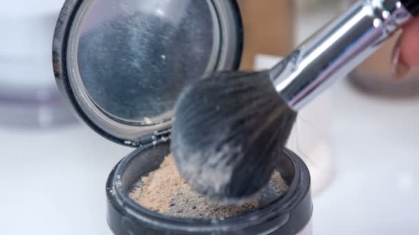 Un maquillador sumerge un pincel en el polvo transparente unas cuantas veces - Metraje, vídeo