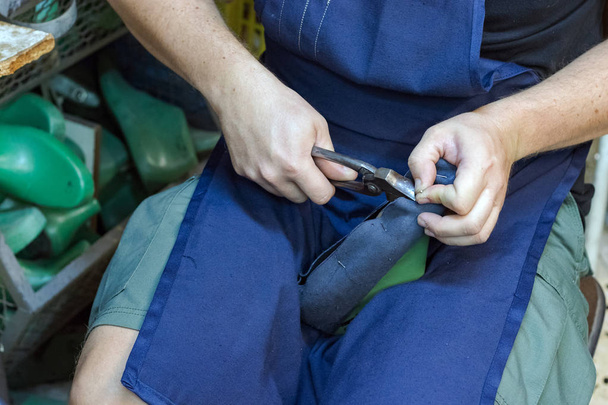 A male shoemaker working on a sole, bending - nailing nails with a shoe plier. - Photo, Image