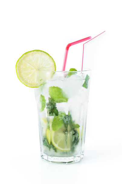 Mojito cocktail in a transparent glass with ice. Recipe for exotic drinks with mint, lime and white rum. Glass with a cocktail on a white background in the rays of the sun. - Foto, imagen