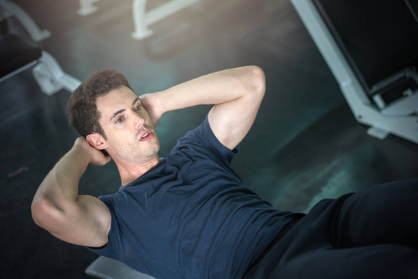 Handsome man exercising doing sit up abdominal exercise in gym - Fotó, kép