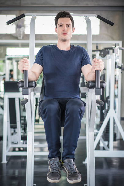 Bonito homem exercitando braço na máquina construtor músculos em fitnes
 - Foto, Imagem