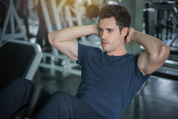 Handsome man exercising doing sit up abdominal exercise in gym - Photo, image