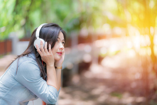 Young beautiful woman enjoying music in the garden listening to  - Foto, Imagem