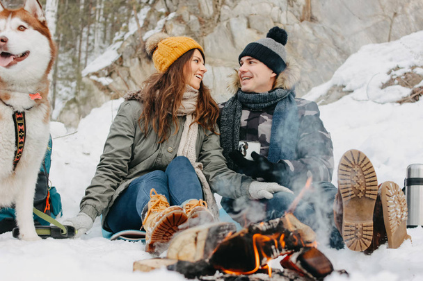 寒い季節に森の自然公園で犬のハスキーと幸せなカップル。旅行冒険愛の物語 - 写真・画像