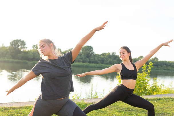 Conceito de harmonia e estilo de vida saudável - Jovens mulheres magras em sportswear praticando ioga ao ar livre
. - Foto, Imagem