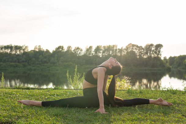 Conceito de harmonia e estilo de vida saudável - Jovem mulher magra em sportswear praticando ioga ao ar livre
. - Foto, Imagem