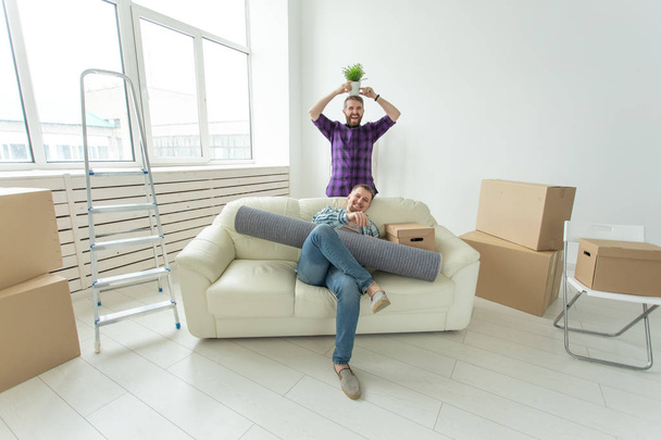 Kaksi opiskelijamiesystävää pitelee tavaroitaan uuden asunnon olohuoneessa. Tupaantuliaiskäsite
 - Valokuva, kuva