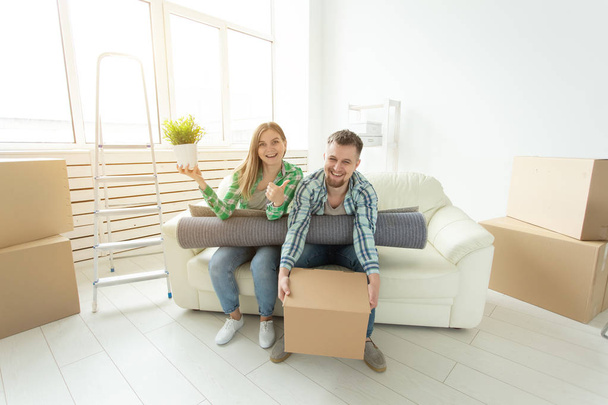 Mozgó, áthelyezés és az új otthon koncepció - fiatal pár szórakozik a kanapén dobozok körül - Fotó, kép