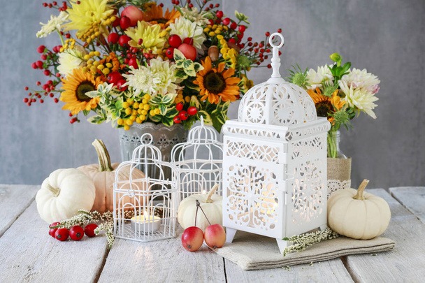 Mooie witte lantaarn, bloemen en pompoenen op tafel - Foto, afbeelding