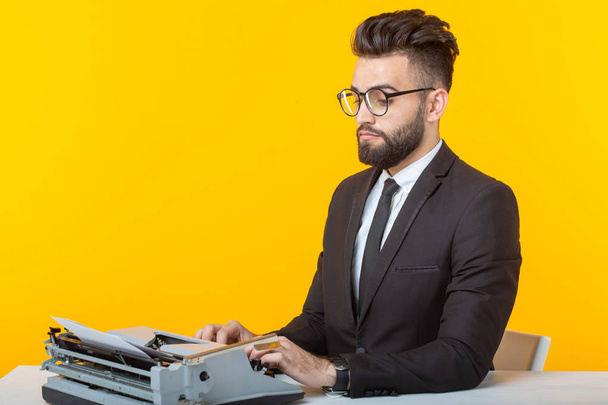 Oldalnézetből egy fiatal, bájos férfi üzletember hivatalos öltözékben és szemüveg gépelés egy írógép szöveget. Az üzleti ügyek és ötletek fogalma. - Fotó, kép