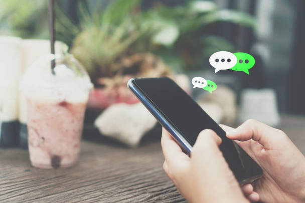 Vrouwen hand met smartphone te typen, babbelen gesprek in chat vak iconen pop omhooggaand. Sociale media maketing concept. - Foto, afbeelding