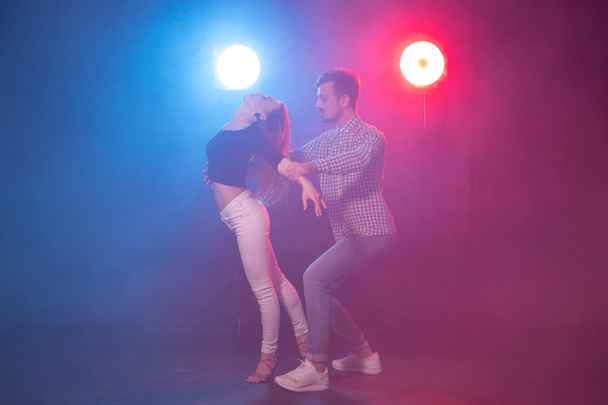 Sosyal dans, bachata, salsa, kizomba, zouk, tango kavramı - Erkek ışıklar üzerinde dans ederken kadın kucaklar - Fotoğraf, Görsel