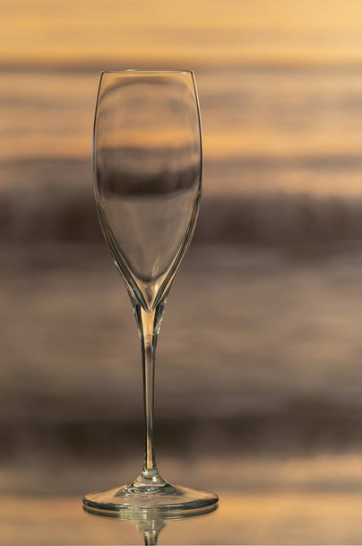 A shiny and elegant glass cup on a glass table and a bottom of the waves of the sea. - Photo, Image