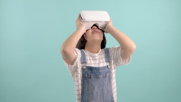 Азиатка в очках виртуальной реальности играет в виртуальную игру на синем зеленом фоне, медленное движение
 - Кадры, видео