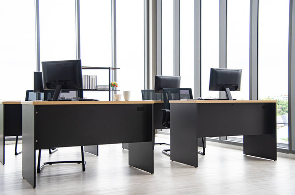 Modern irodai belsőépítészet asztallal, számítógéppel, monitorval, nagy üvegablak a szoba körül emberek nélkül - Fotó, kép
