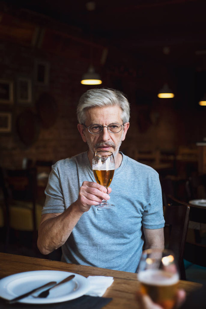 Pensive man with a beer in a bar - Фото, зображення