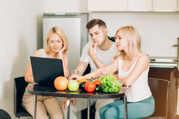 Friends using laptop in kitchen - Фото, изображение