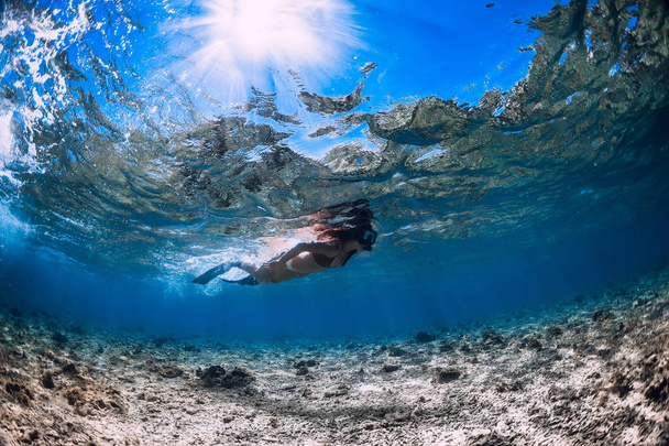 Mulher mergulhadora livre com barbatanas desliza sobre corais em mar azul
. - Foto, Imagem
