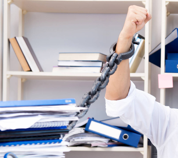 Employee attached and chained to his desk with chain - Photo, Image