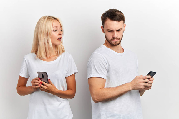 blonde woman prying into her boyfriends phone - Фото, зображення