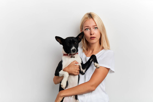 scared shocked woman carries lovely dog, dressed in white stylish T-shirt - Foto, afbeelding