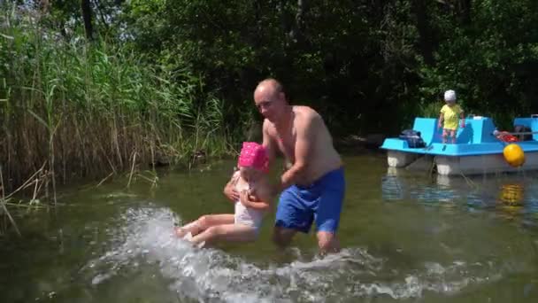 Dad plays with daughter in water. Son standing on catamaran. Gimbal motion - Footage, Video