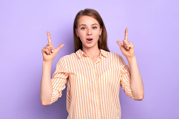 Positive funny girl with appealing appearance pointing up index fingers - Photo, image