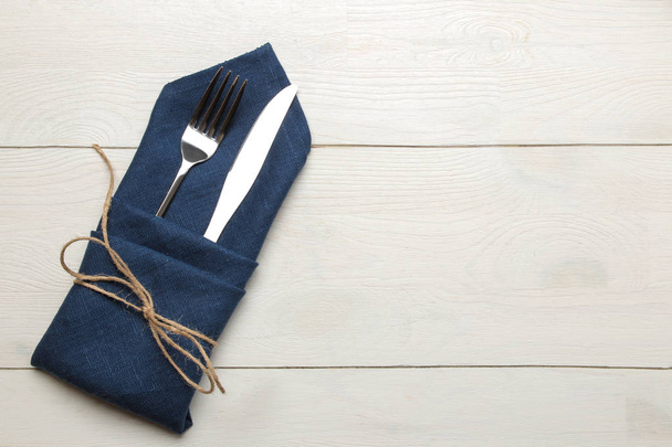 tabel instelling. Bestek. Vork, mes in een blauwe servet op een witte houten tafel. Top View - Foto, afbeelding
