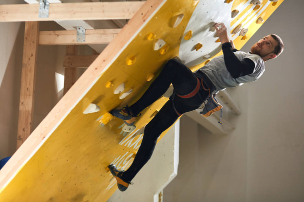 Athletic male boulderer with physical disability climbing at steep rock wall - Foto, Imagen