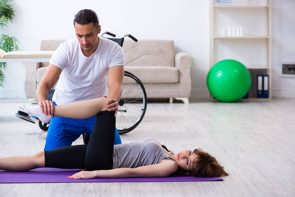 Male physiotherapist doing exercises with injured woman on floor - Φωτογραφία, εικόνα