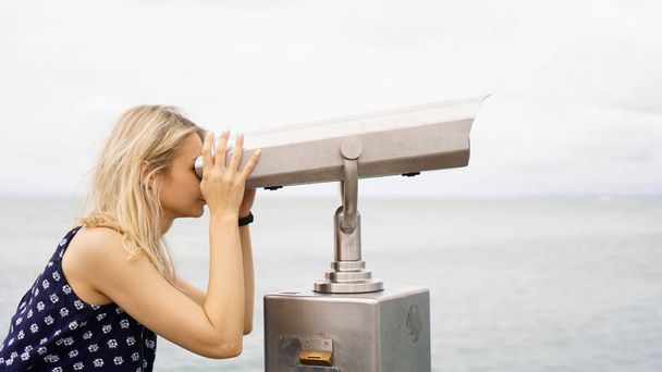 Woman standing on cruise liner deck and looking in binocular, half body - Fotó, kép
