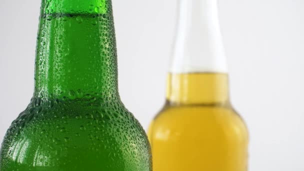 Kaksi pulloa olutta vesipisaroilla valkoisella taustalla. 4k lähikuva voisi juoda alkoholia läpinäkyvissä ja vihreissä pulloissa
. - Materiaali, video