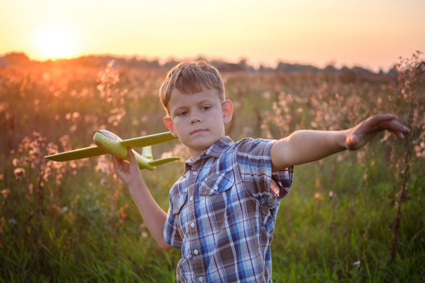 cute boy playing airplane on a summer evening against the sunset - Foto, immagini