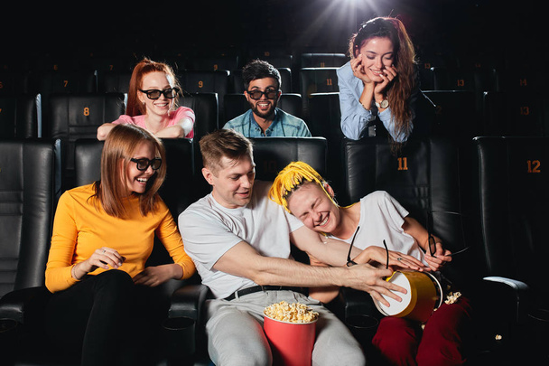 attraktives junges Paar, das Spaß mit Popcorn hat, während andere ihnen zuschauen - Foto, Bild