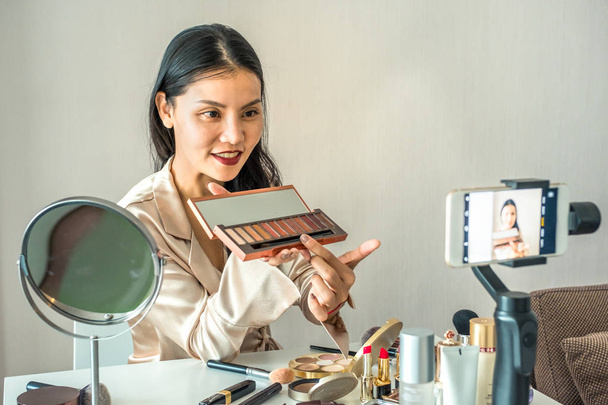 Mujer asiática grabando con un teléfono para hacer las paces. Vender productos o taller concepto en línea
 - Foto, Imagen