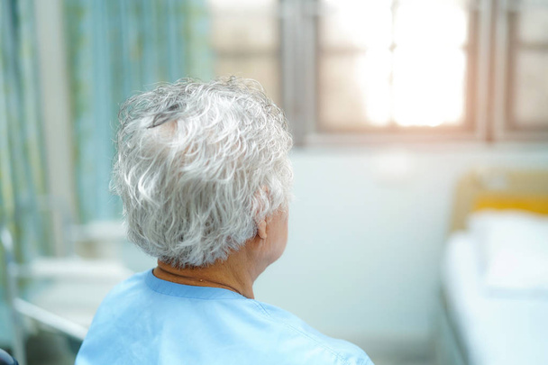 Starší Asijská nebo stará ženská, pacientka sedí na posteli v ošetřovatelské nemocnici s nadějí a čeká na příbuzného: zdravý silný lékařský koncept. - Fotografie, Obrázek