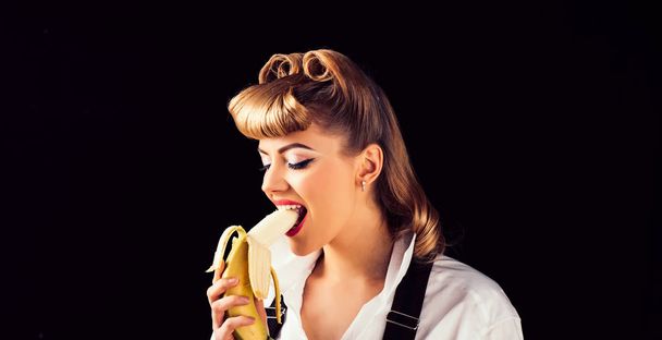 Девушка с бананом. Молодая женщина кусает банан. Витамины и питание. Еда. Девушка ест банан на черном фоне изолированы
. - Фото, изображение
