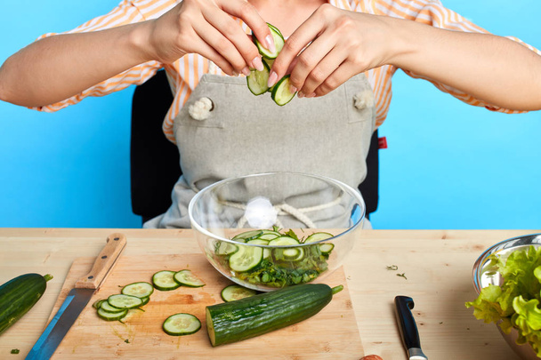 Unrecognizable woman preparing fresh smoothie, using raw sliced cucumbers - Фото, изображение