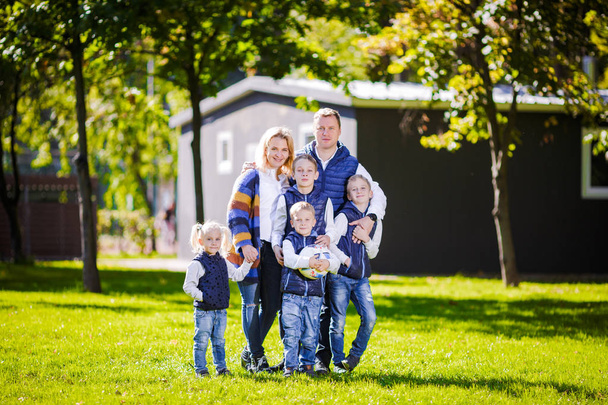 Happy Family Outdoors. Happy Caucasian family standing outside their house and hugging. Family with four children in front house. Big happy family stands beside their house smiling and looking camera - Photo, Image